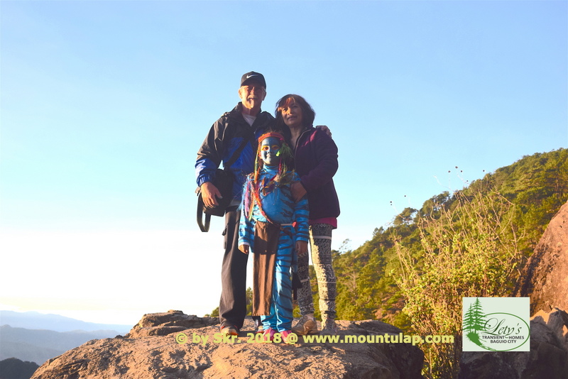 Mt. Ulap, In a mountain landscape at dawn on the 2nd. Tourist Spot two Senior Citizens with Avatar girl standing on top of the Rock ledge Corral-Rock.